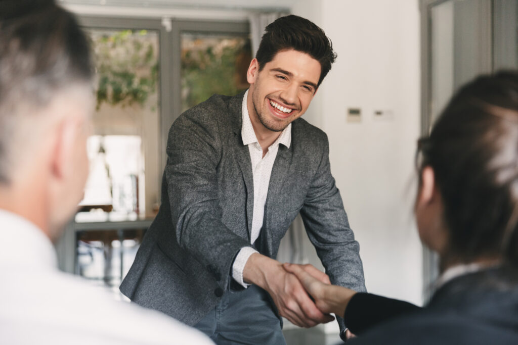 Business, Career And Placement Concept   Happy European Man Wearing Suit Rejoicing And Shaking Hands With Group Of Employee, When Was Recruited During Interview In Office